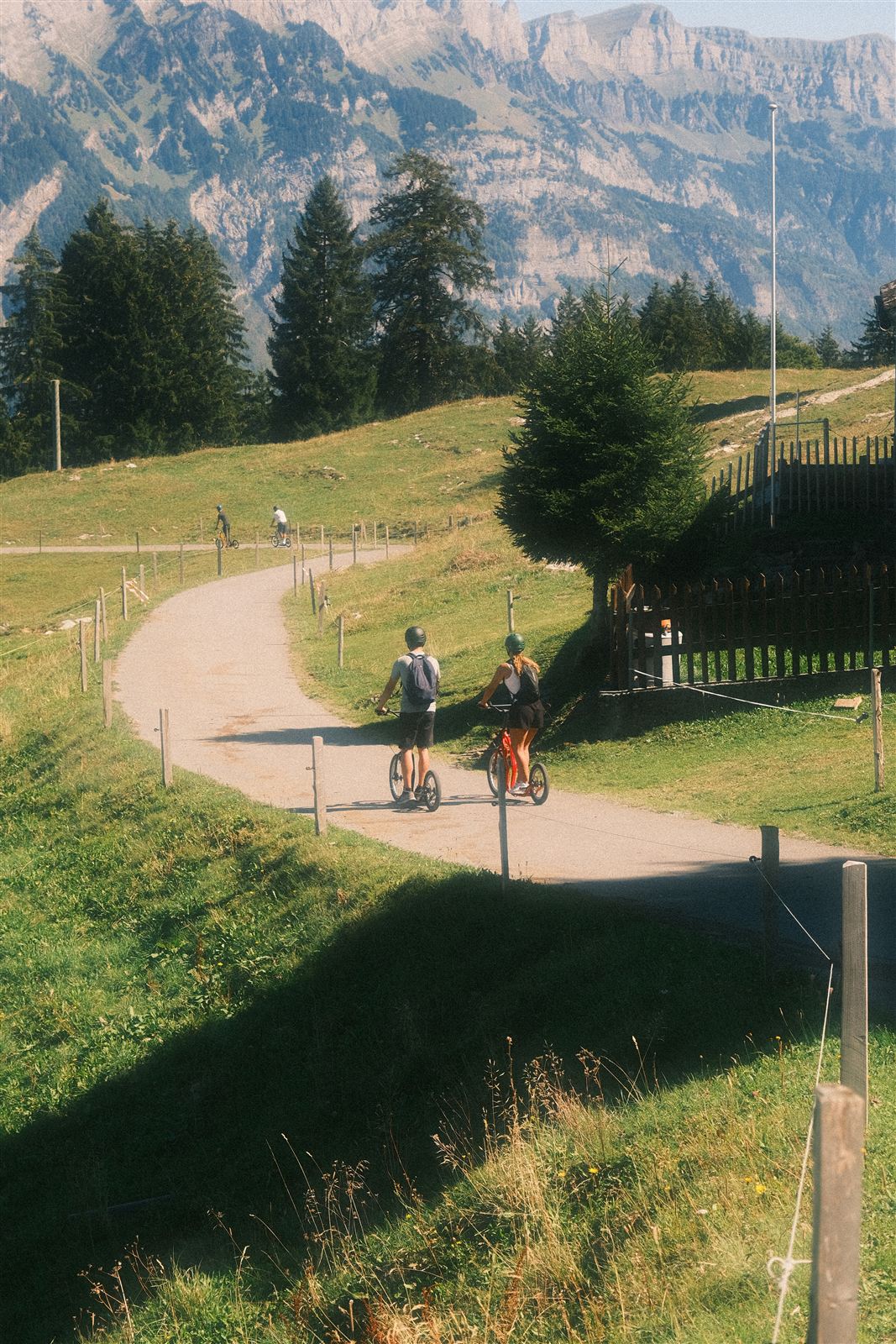 Zwei Trottinett-Fahrer auf dem Bergweg mit Bergkulisse
