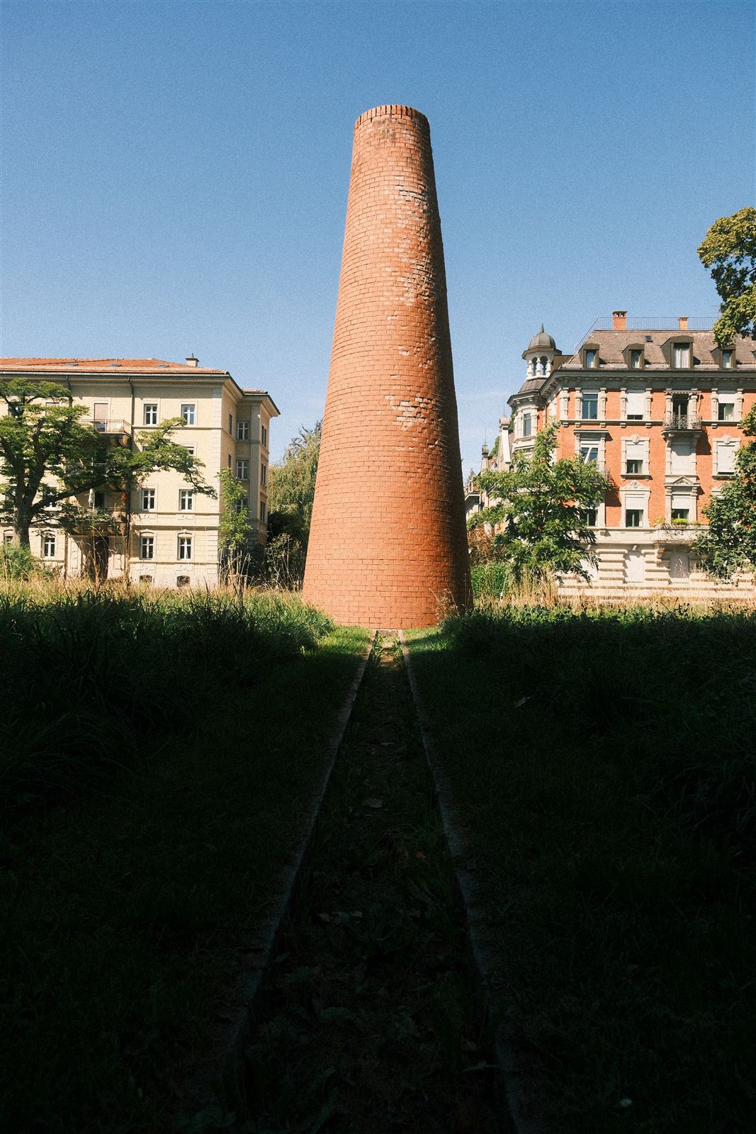 Backsteinschornstein zwischen Bäumen und Altstadthäusern