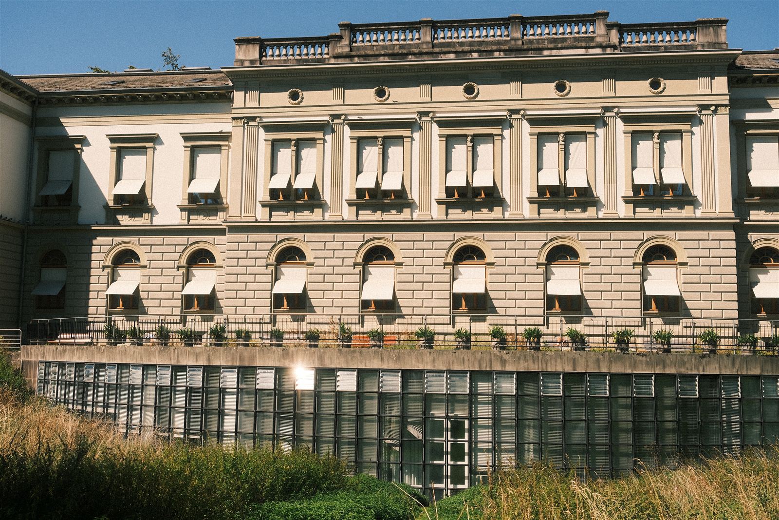 Klassizistische Fassade mit Fensterläden und verglastem Sockelgeschoss